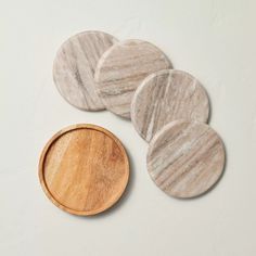 four marble coasters and a wooden plate on a white surface