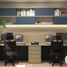 an office with two desks and three monitors on it's sides, in front of a bookshelf