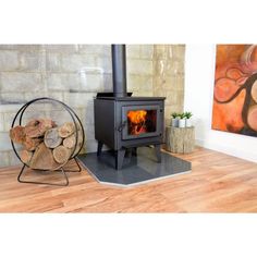 a wood burning stove sitting on top of a hard wood floor next to a pile of logs