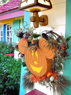 a mickey mouse pumpkin hanging from the side of a house