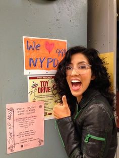 a woman with glasses pointing at a sign