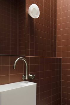 a white sink sitting next to a brown tiled wall