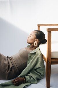 a woman laying on the ground next to a chair with her legs crossed and head tilted