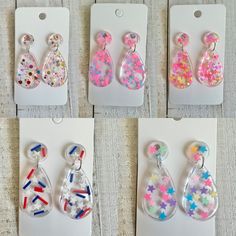 four different designs of earrings are shown in plastic packaging on a table with white tags