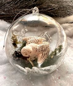 a glass ornament with an owl in it's mouth and snow on the ground