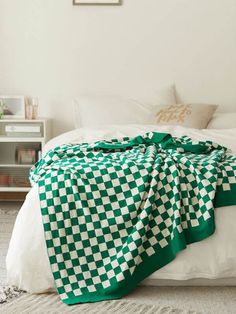 a green and white blanket sitting on top of a bed