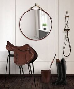 a horse saddle sits in front of a mirror on the wall next to a pair of boots