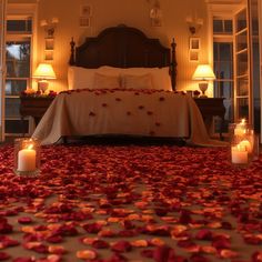 a bed with rose petals and candles on the floor