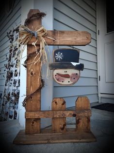 a wooden snowman with a hat and scarf hanging from it's back