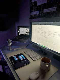 a computer desk with a tablet, keyboard and mouse on it in front of two monitors