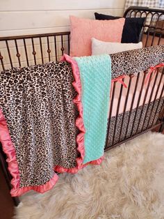 a baby crib with pink and black bedding, leopard print blanket, and cheetah rug