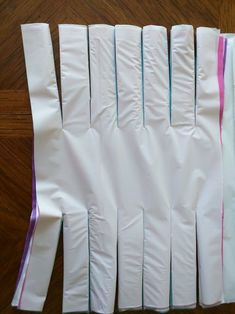 several pieces of white paper are lined up on the floor with purple and pink strips