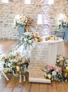 a table set up with flowers and candles in front of a stone wall for a wedding reception