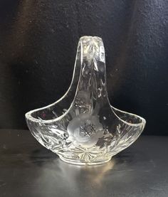 a clear glass bowl sitting on top of a table next to a black wall in the background