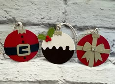 three christmas ornaments hanging on a brick wall