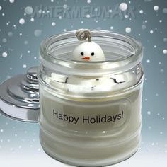 a candle with a snowman on it sitting in a jar that says happy holidays