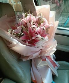 a bouquet of pink flowers sitting in the back seat of a car with ribbons on it