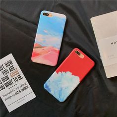 two phone cases sitting on top of a bed next to a notepad and envelope