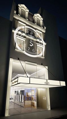 a large clock on the side of a building at night with windows lit up in front of it