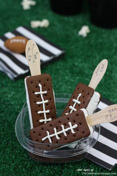 two football shaped ice cream pops are in a glass bowl on a green tablecloth