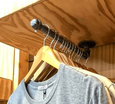 clothes hangers and t - shirts on wooden racks