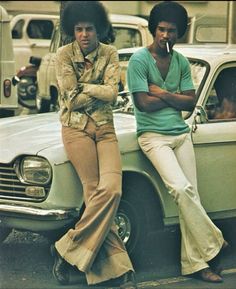 two men sitting on the hood of a car