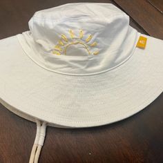 a white hat with the sun embroidered on it sitting on top of a wooden table