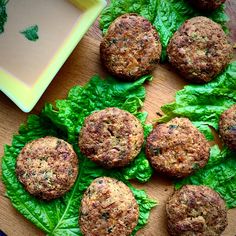 some meatballs are sitting on lettuce leaves next to a bowl of sauce