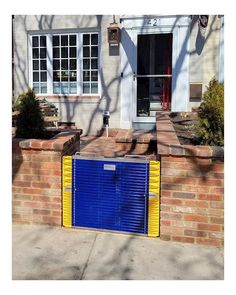 a blue and yellow gate is in front of a brick wall with a white door