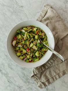 a white bowl filled with chopped vegetables on top of a marble counter next to a napkin