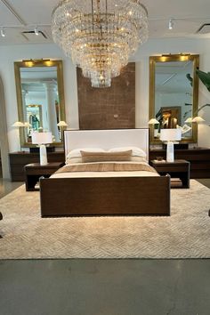 a large bed sitting in the middle of a room with chandelier above it