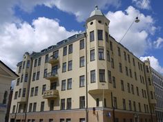 an apartment building with many windows and balconies on the top floor, in front of a cloudy blue sky