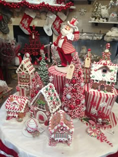 a table topped with lots of gingerbread houses and santa clause on top of it