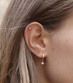 a close up of a woman's ear with small stars on the top of it