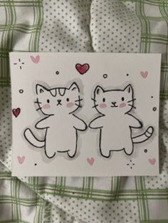 two cats are standing next to each other on a sheet of white paper with hearts