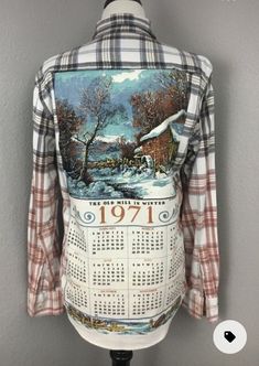 a plaid shirt with a painting on the back and numbers printed on the front, sitting on a mannequin's head