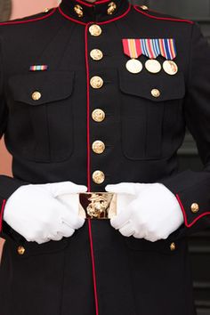 a man in uniform is holding his hand on his chest and wearing white gloves with gold buttons