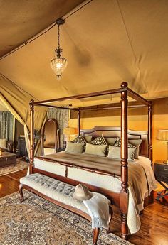 a canopy bed sitting inside of a bedroom on top of a wooden floor