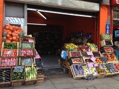 there are many fruits and vegetables on display in the storefronts at this street side market