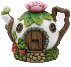 a teapot shaped like a house with a pink flower on it's roof