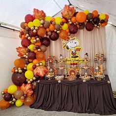 a table topped with lots of balloons and desserts next to a white tented wall