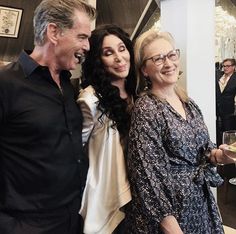 three people standing next to each other with wine glasses in their hands and smiling at the camera