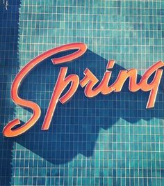 the words springs written in orange and blue on a swimming pool tile with water splashing around it