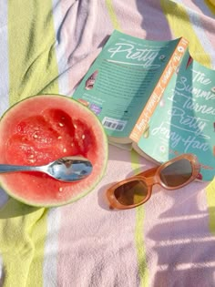 watermelon and sunglasses on a towel with a book