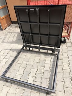 a black metal frame sitting on top of a brick floor next to a shopping cart