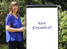 a woman standing next to a sign that says get creative