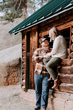 a man and woman leaning against the side of a log cabin