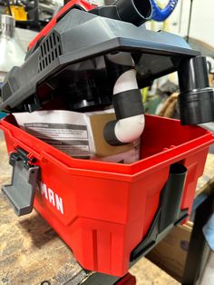 a red tool box filled with tools on top of a wooden table