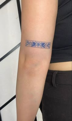 a woman's arm with a tattoo on it that has blue flowers and leaves