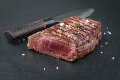 a piece of steak sitting on top of a cutting board next to a knife